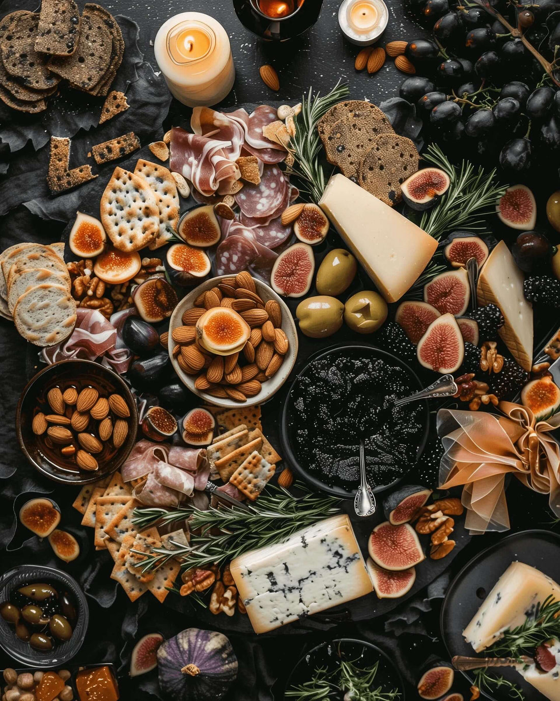 Black Garlic Charcuterie board with cheeses, figs, olives, almonds, crackers, and candles for a hauntingly delicious spread.