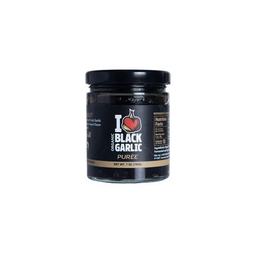 Jar of organic black garlic puree on a white background