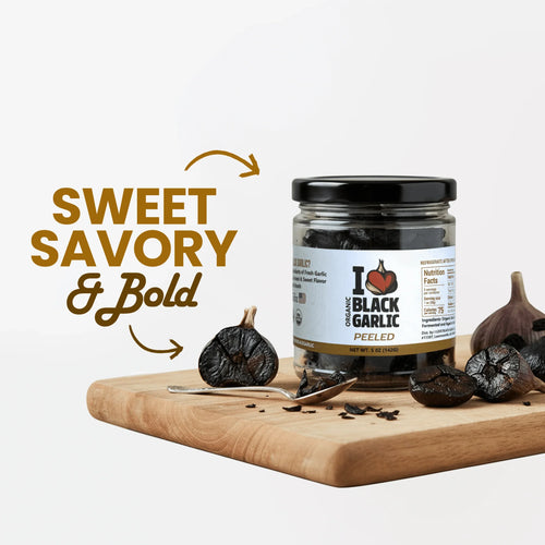 Jar of Organic Peeled Black Garlic Cloves – 5 oz on a wooden board with whole black garlic and cloves, emphasizing sweet and savory flavor.